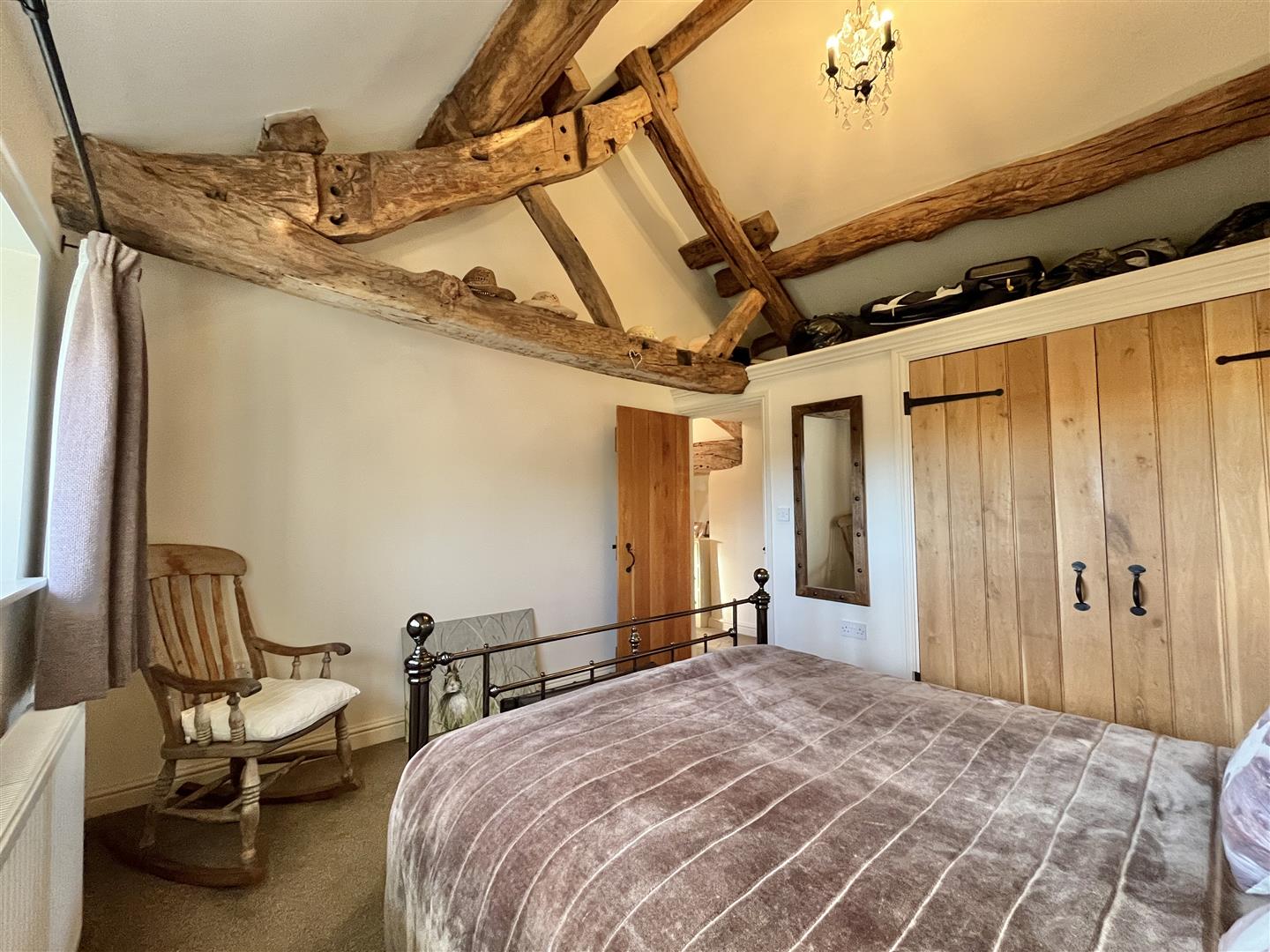 A bedroom with a built-in wardrobe beneath a vaulted ceiling